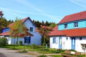 ein weißes Haus mit einem roten Dach und einer Bank in der Unterkunft Ferienwohnung Bakenberg auf Rügen (So) in Dranske