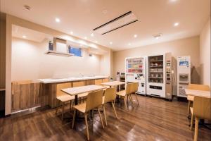 a dining room with tables and a kitchen with appliances at HOTEL MYSTAYS Sapporo Nakajima Park Annex in Sapporo