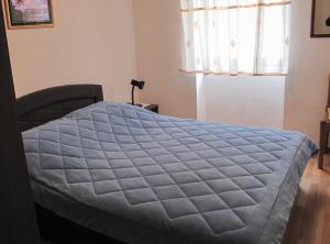 a bedroom with a bed with a blue quilt at Bright and Modern: Fully Furnished Krk Apartments with Private Parking in Vrh