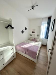 a bedroom with a bed and a dresser and a window at Falcon Apartman Tatabánya in Tatabánya