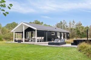a black house with a patio and a lawn at Feriehus 1066 in Ringkøbing