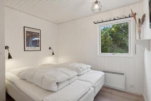 a white bedroom with two beds and a window at Feriehus 1066 in Ringkøbing