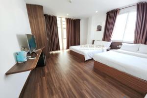 a hotel room with two beds and a desk at Khách sạn Kinh bắc in Ho Chi Minh City