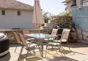 un tavolo, sedie e un ombrellone in un patio di Balchik Sea View Escape 5BR Luxury with Hot Tub & Free Parking a Balchik