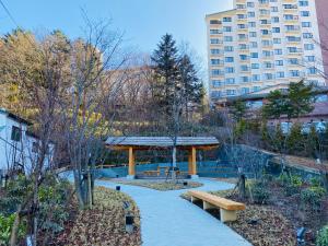 a park with benches and a pavilion and a building at Kusatsu KOTODAMA in Kusatsu