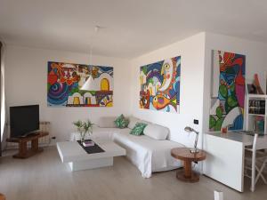 a white living room with paintings on the walls at Villa Barbara in Giardini Naxos