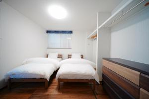 a bedroom with two beds and a dresser in it at Casa Antonio A モダン空間 駅近&空港バス 駐車場付 in Sapporo