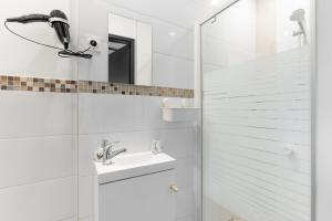 a white bathroom with a sink and a shower at Le Petit Enclos - Appt climatisé parking privé in Vaulx-en-Velin