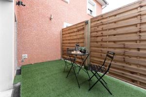 a patio with a table and chairs and a fence at Le Petit Enclos - Appt climatisé parking privé in Vaulx-en-Velin +5 photos