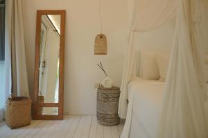 una camera da letto con un letto bianco e uno specchio di Joy Canggu a Canggu