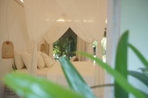 una camera con letto bianco e tende di Joy Canggu a Canggu