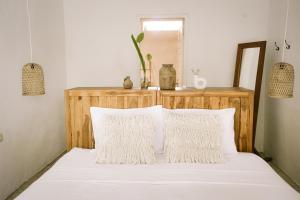 una camera da letto con un letto con lenzuola e cuscini bianchi di Joy Canggu a Canggu