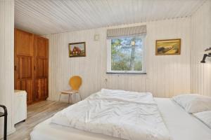 a bedroom with a white bed and a window at Feriehus 1086 in Ulfborg