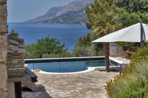 una piscina con sombrilla y vistas al agua en Villa Relax Brela - Makarska Exklusiv, en Brela