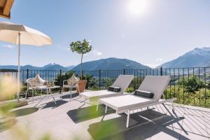 Un patio con dos sillas y una mesa y una sombrilla. en Hotel Hohenwart, en Scena