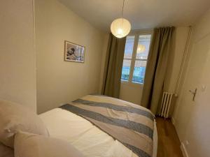 een kleine slaapkamer met een bed en een raam bij Ajania, Appt avec parking et petit jardin privé in Caen