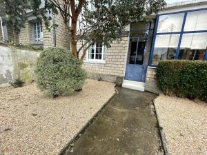 een huis met een blauwe deur en een struik bij Ajania, Appt avec parking et petit jardin privé in Caen
