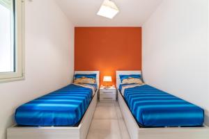Dos camas en una habitación con paredes naranjas. en Dimora da mare, en Marina di Pescoluse