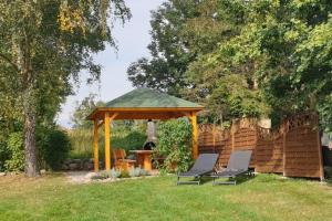a gazebo with two chairs in a yard at Ferienwohnungen unterm Reetdach m Terras o Balk u Sauna in Middelhagen