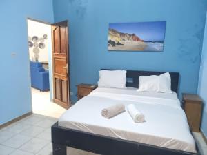 a blue bedroom with a bed with two rolled towels on it at VINCE SALY 3 in Sali Nianiaral