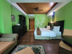 1 dormitorio con cama blanca y paredes verdes en Lee Boutique Hotel Tagaytay, en Tagaytay