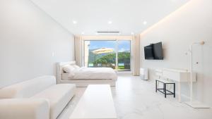 un salon blanc avec un canapé et une télévision dans l'établissement Gapyeong staysumok pool villa pension, à Gapyeong