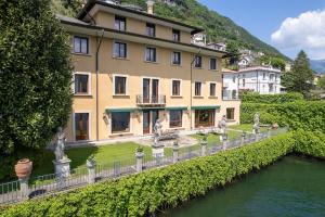 un grand bâtiment avec statues en face d'une rivière dans l'établissement Lakefront 1800s Villa Private Dock, Art Luxury, à Carate Urio