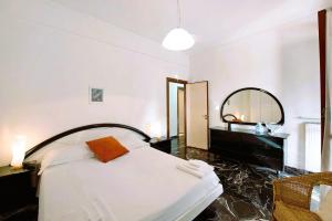 Un dormitorio con una cama blanca y un espejo. en Casa Ester, en Arenzano