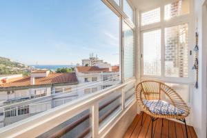 SantanaにあるGuestReady - Lovely Experience in Sesimbraの大きな窓のある客室で、籐の椅子が備わります。