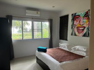 een slaapkamer met een bed met een clownsschilderij aan de muur bij Shanti samui Resort in Laem Sor +61 foto's