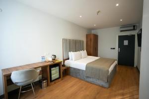 Un dormitorio con una cama, un escritorio y una silla. en Business Life Hotel Güneşli, en Estambul