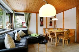 un salon avec un canapé en cuir noir et une table dans l'établissement Gästehaus Seewald- Ferienwohnung 1 "Ahorn", Schluchsee, Blasiwald, à Schluchsee