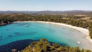 an aerial view of a beach with a boat in the water at La Mandragora, belle Villa pour 6 personnes avec piscine à débordement et vue mer à La Londe-les-Maures in La Londe-les-Maures