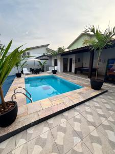a swimming pool with palm trees and a house at Casa no Condomínio CenterVille in Bertioga