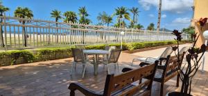 eine Terrasse mit Tisch und Stühlen sowie Strand in der Unterkunft Verdadeiro Pé na Areia in Santos