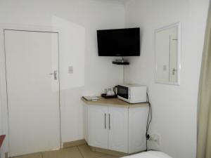 a white room with a television and a microwave at Majestic in Kokstad