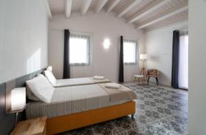 a bedroom with a large bed and two windows at Relais Tenuta Santori in Cossignano
