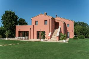 a large pink house with a grass yard at Relais Tenuta Santori in Cossignano