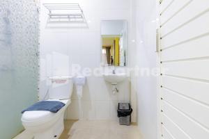 a white bathroom with a toilet and a sink at De Malang Sweet Homestay Syariah Mitra RedDoorz in Malang +64 photos