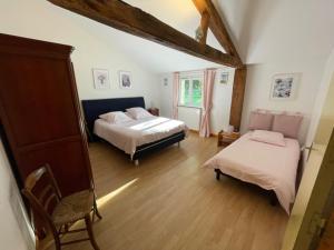 Un dormitorio con dos camas y una silla y una ventana. en Les gîtes de la Font, en Usson-du-Poitou 7 fotos más