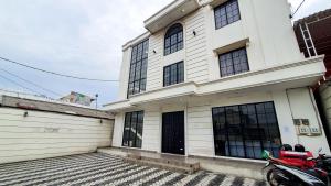 a white building with a motorcycle parked in front of it at La'Rissa Residence by ARBA in Karawang