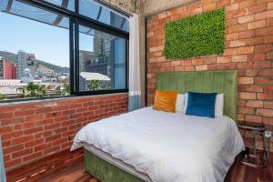 - une chambre dotée d'un mur en briques et d'un lit avec des oreillers colorés dans l'établissement Manhattan-style 2-bedroom apartment, au Cap