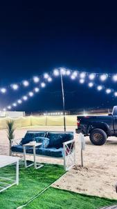 un sofá azul sentado bajo una tienda con un camión en Big bear camping, en Nafīr 2 fotos más