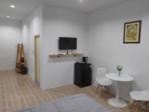 a living room with a tv on a white wall at Phudis Guest House in Ban Khlong Haeng
