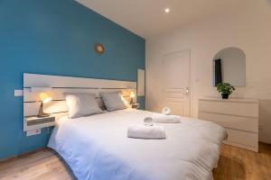 a bedroom with a large white bed with a blue wall at L'appart du Général in Elbeuf