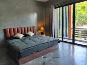 a bedroom with a bed and a large window at Phudis Guest House in Ban Khlong Haeng
