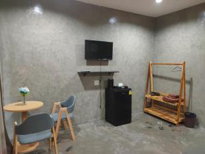 una camera con televisore, tavolo e sedie di Phudis Guest House a Ban Khlong Haeng