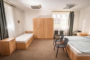 a room with two beds and chairs in it at Ipoly-Velo Vendégház in Balassagyarmat