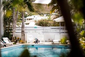 a swimming pool with white chairs and a white fence at Appartements Le Bleu des Roches Noires in Saint-Gilles les Bains