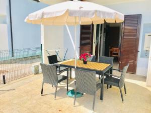 a wooden table with chairs and an umbrella at Isca Calabretta Apartments M28 in Isca sullo Ionio